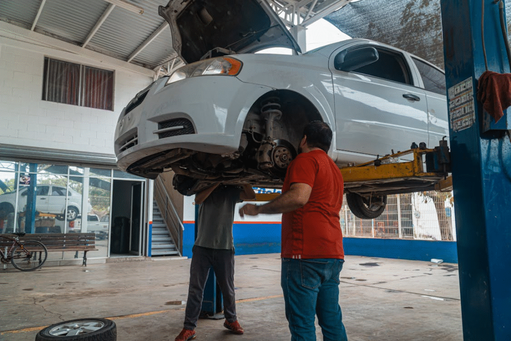 Technician inspecting car suspension during chassis maintenance at auto repair shop.