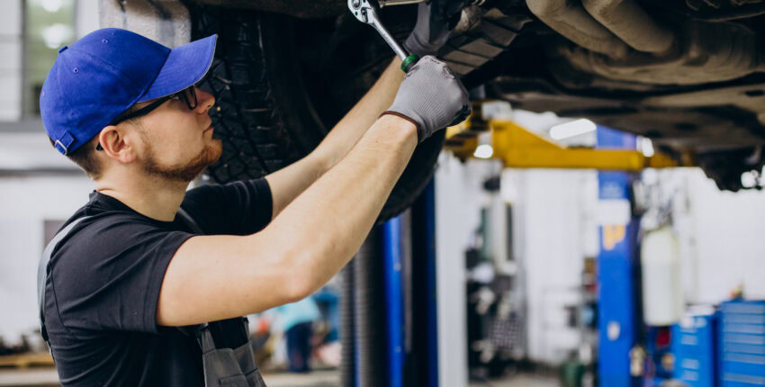 Auto repair technician checking under a vehicle on a hydraulic lift at Hillside Auto Clinic.