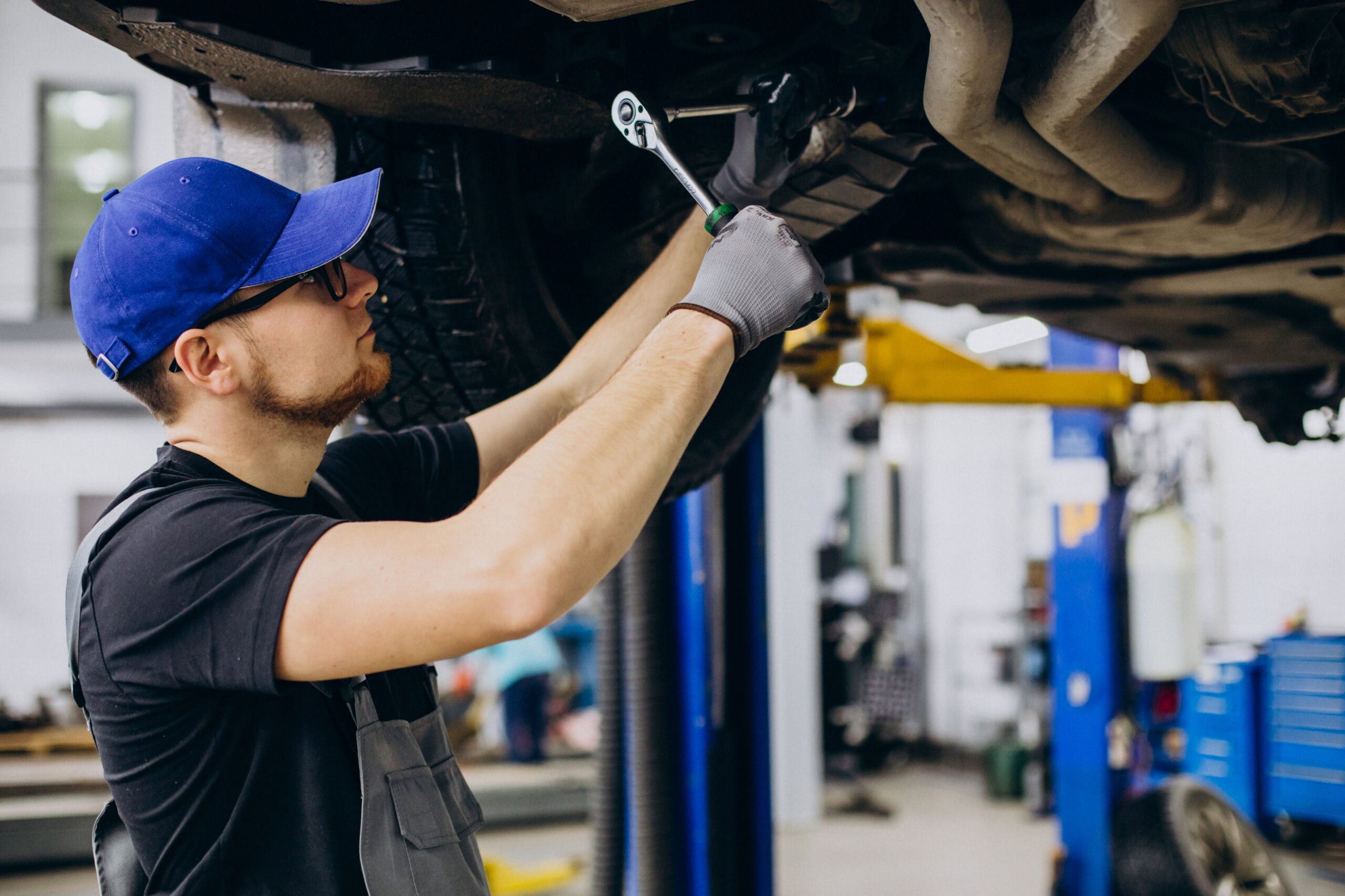 Auto repair technician checking under a vehicle on a hydraulic lift at Hillside Auto Clinic.