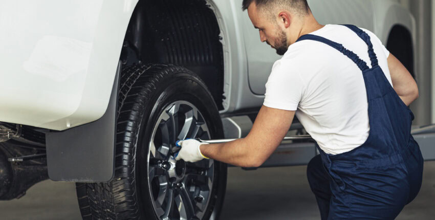 Auto technician inspecting a vehicle's tire for damage or wear.