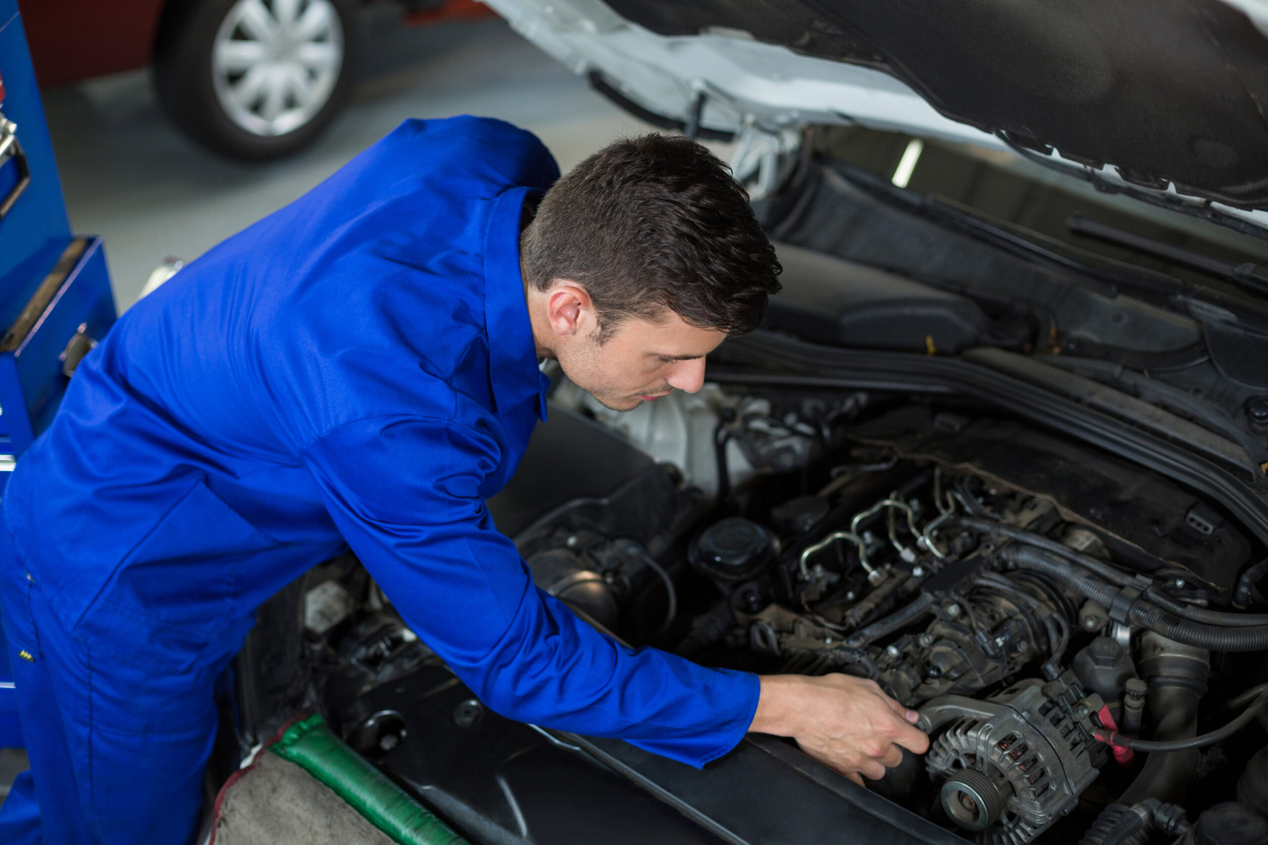 Experienced mechanic working on car engine rebuild under the hood.