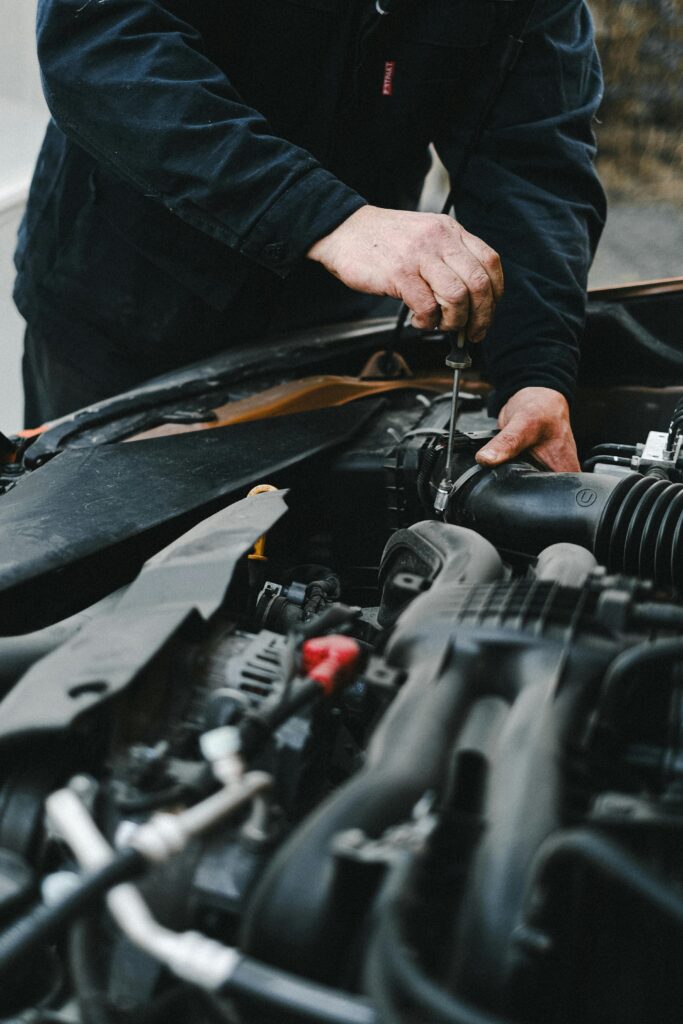Automotive mechanic inspecting car engine for repairs at Hillside Auto Clinic.