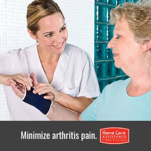 Caregiver massaging elderly hand to relieve arthritis pain
