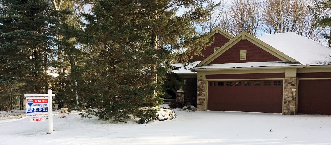 snowy exterior of home with for sale sign