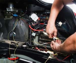 Technician working on car wiring and electronics at Imola Motorsports.