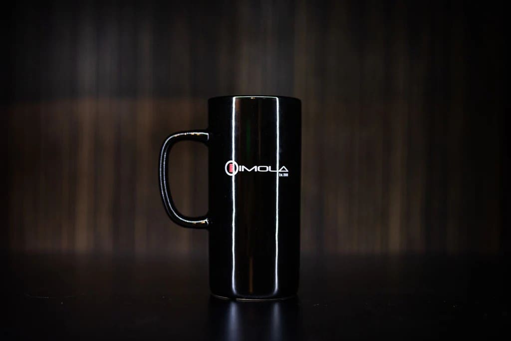 Black ceramic mug with Imola Motorsports logo for racing fans.