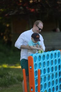 An adult and child playing giant Connect Four outdoors at Inchmarlo, a perfect family-friendly destination.