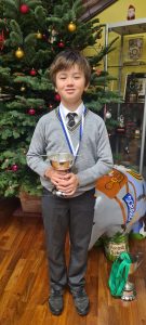 Young boy holding trophy, celebrating festive achievements at Inchmarlo Christmas event.