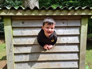 Child plays through a wooden outdoor playhouse at Inchmarlo.