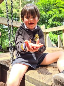 Young child enjoying outdoor play at Inchmarlo, surrounded by lush greenery and nature.