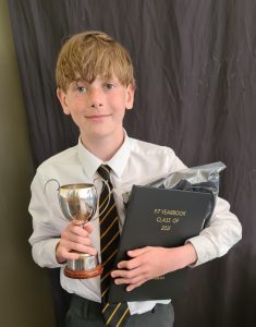Young boy holding award and certificate, celebrating achievement at Inchmarlo School.
