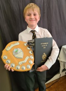 Young boy holding award trophy and certificate, celebrating achievement at Inchmarlo School.
