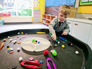 Young boy playing with colorful sensory toys in a classroom.