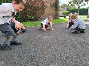 Children drawing on outdoor playground surface at Inchmarlo school.