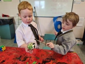 Two young boys playing with a marble race toy in a classroom setting.