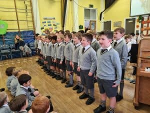 Children singing in school assembly, engaging students in a musical performance at Inchmarlo.