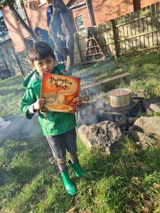 Child cooking outdoors with pumpkin soup outdoors, enjoying nature.
