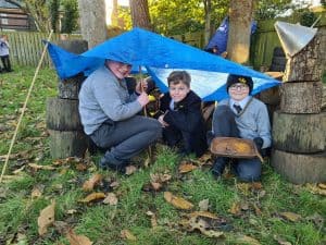 Children playing outdoors under a blue tarp at Inchmarlo estate with autumn leaves.