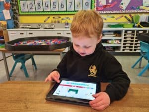 Young boy using a tablet in classroom.