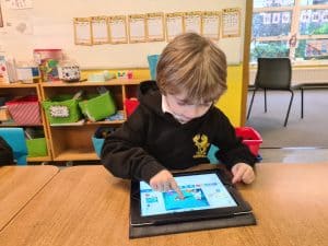 Young child using a tablet in a classroom setting.