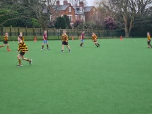 Children playing soccer on Inchmarlo sports field in a lush green setting.
