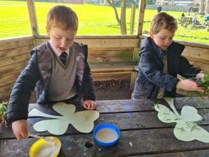 Two children engaging in outdoor educational activities in a woodland setting at Inchmarlo.