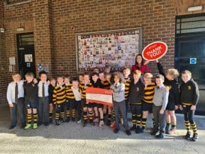 Children holding a fundraising sign outside school.