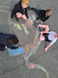Children drawing colorful chalk art on outdoor pavement at Inchmarlo.