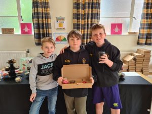 Three boys at Inchmarlo School holding a gift box.