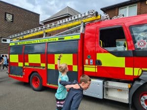 Children playing near Inchmarlo fire truck at community event.