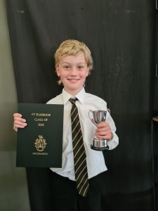Happy student holding trophy and certificate at Inchmarlo school.