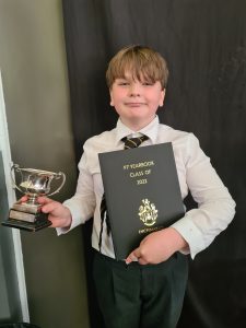 Young boy holding awards and certificate, celebrating success at Inchmarlo School.