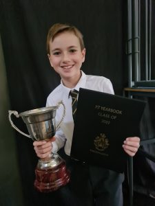Young boy holding trophy and certificate at Inchmarlo event, showcasing excellence and achievement.