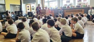 Children in school uniforms attending a classroom assembly.