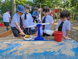 Children playing with sand at Inchmarlo outdoor play area in a lush green park.