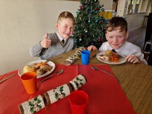 Happy kids enjoying festive meal at Inchmarlo in front of Christmas tree.