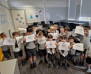 Children holding signs in classroom at Inchmarlo School, promoting education and student engagement.