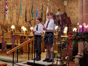 Young students singing at Inchmarlo school event in a historic hall.