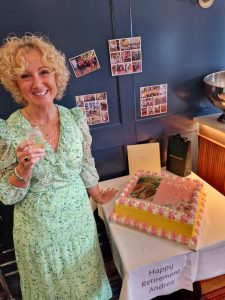 Woman celebrating retirement with cake and champagne in a cozy setting.