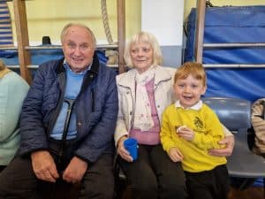 Group of smiling elderly people and a young boy at Inchmarlo care facility, promoting community and elderly support services.