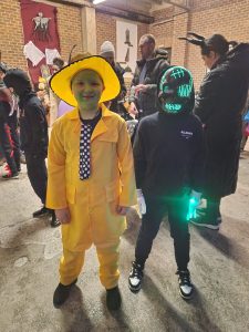 Young girl in yellow Scout uniform at Inchmarlo outdoor event, surrounded by peers and adults.