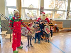 Festive holiday event at Inchmarlo with Santa, children, and reindeer in a cheerful indoor setting.