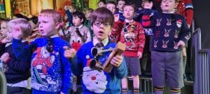 Children singing Christmas carols at Inchmarlo, festive outdoor performance.