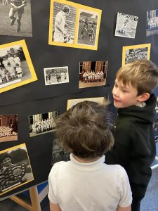 Two children viewing historical black-and-white photographs displayed on a wall.