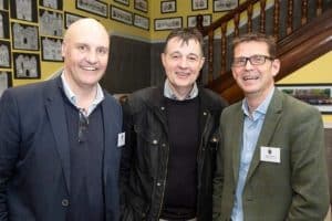 Three smiling men in business attire at Inchmarlo, a welcoming hotel in Scotland.