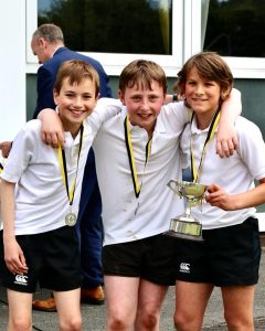 Young boys celebrating with medals and trophy at Inchmarlo golf event.