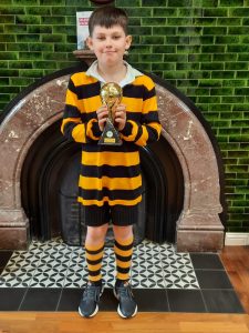 Young boy holding trophy in sports outfit at Inchmarlo school event, celebrating achievement and success.