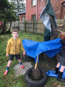 Child planting a tree in Inchmarlo garden, surrounded by a wooden fence, showcasing outdoor activities and nature conservation.