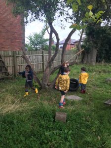 Children exploring outdoor garden at Inchmarlo School, with trees and fencing in the background.