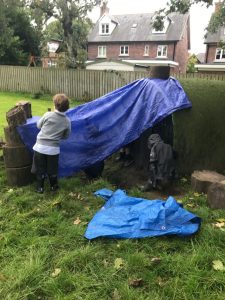 Children enjoying outdoor play with a blue tarp at Inchmarlo.